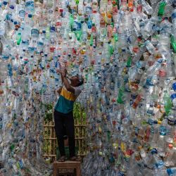 Un activista indonesio de ECOTON (observación ecológica y conservación de humedales) prepara una instalación hecha con plástico usado, incluidas 4.444 botellas, recogidas del río en Gresik, para concienciar a la población sobre los residuos de plástico en los ríos y océanos. | Foto:Juni Kriswanto / AFP