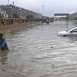 Un hombre empuja su motocicleta por una calle inundada después de una fuerte lluvia en Karachi.  | Foto:AFP