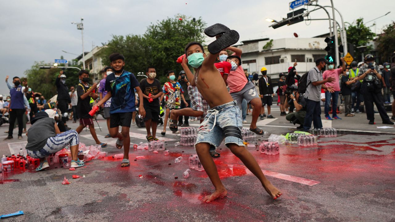 Jóvenes manifestantes antigubernamentales lanzan botellas de pintura roja a la policía durante una manifestación en Bangkok, mientras los activistas piden la dimisión del primer ministro de Tailandia, Prayut Chan-O-Cha, por la gestión gubernamental de la crisis del coronavirus Covid-19. | Foto:Jack Taylor / AFP