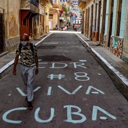 Un hombre camina sobre un cartel escrito en el pavimento que dice "Viva Cuba" sobre una calle en La Habana. | Foto:Yamil Lage / AFP
