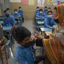 Un trabajador sanitario inocula a un estudiante con una dosis de la vacuna de Pfizer contra el coronavirus Covid-19 en una escuela de Lahore, después de que el gobierno iniciara una campaña para vacunar a los niños mayores de 12 años. | Foto:Arif Ali / AFP