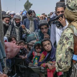 Unas personas se paran cuando miembros talibanes los detienen mientras se apresuran a pasar a Pakistán desde la frontera con Afganistán en Spin Boldak. | Foto:Bulent Kilic / AFP