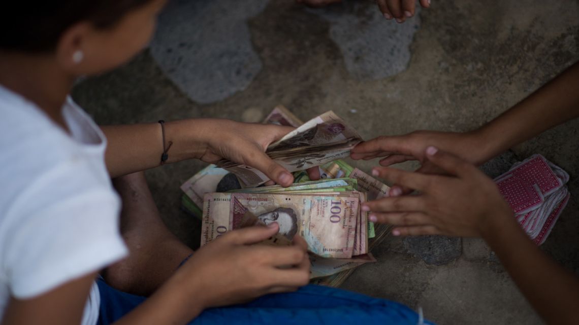 Children play cards and bet with unused Venezuelan bolivar bills on a street of Puerto Concha town, Zulia state, Venezuela, on September 9, 2021. 