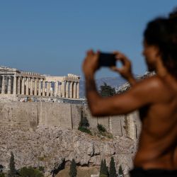 Un hombre hace una foto desde una colina con vistas al sitio arqueológico de la Antigua Acrópolis en Atenas, Grecia. | Foto:DAVID GANNON / AFP