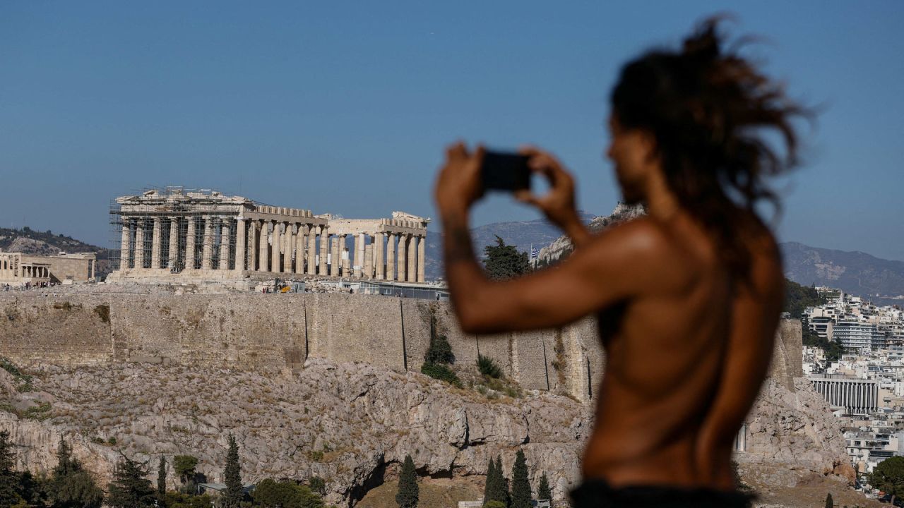 Un hombre hace una foto desde una colina con vistas al sitio arqueológico de la Antigua Acrópolis en Atenas, Grecia. | Foto:DAVID GANNON / AFP