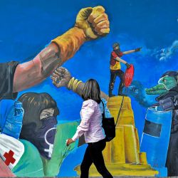 Una mujer pasa junto a un mural en apoyo a las protestas contra el gobierno, en una calle de Cali, Colombia. | Foto:Luis Robayo / AFP