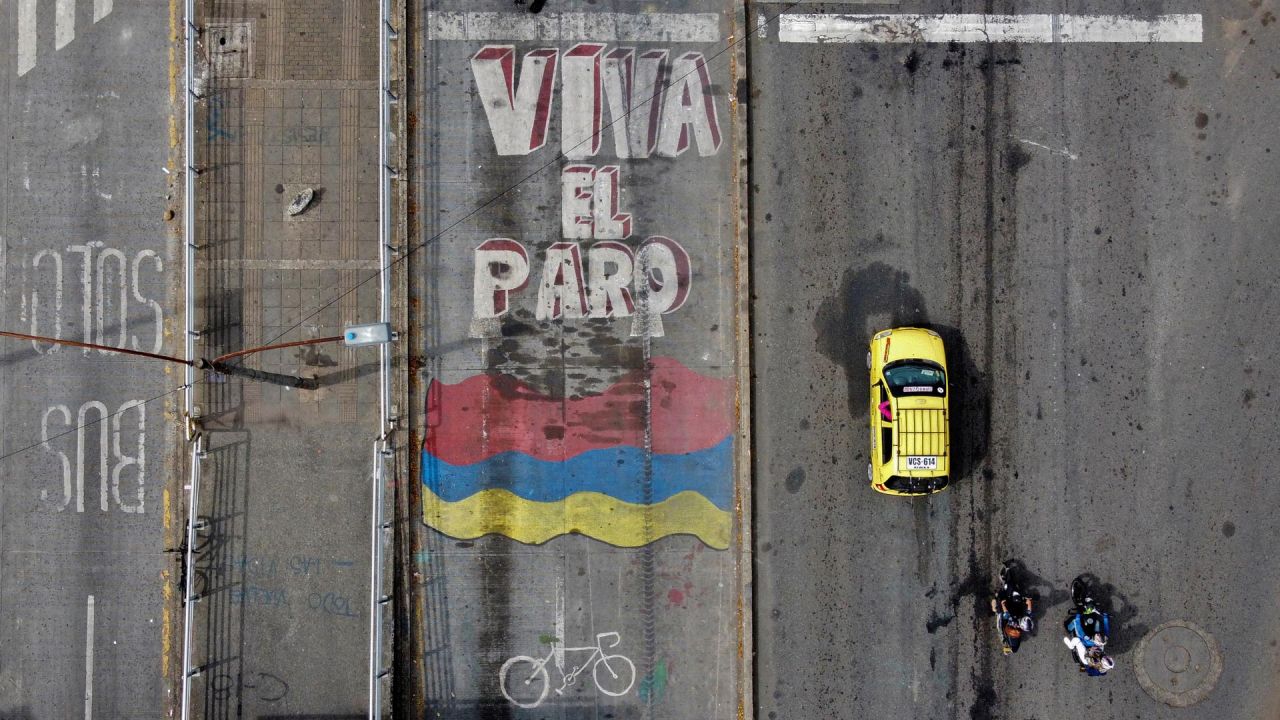 Vista aérea de un coche y motocicletas que pasan por delante de una pintura en la que se lee "Viva la huelga" en una calle de Cali, Colombia. | Foto:Luis Robayo / AFP