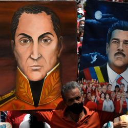 Un partidario del presidente de Venezuela, Nicolás Maduro, sostiene retratos de él y del héroe nacional de Venezuela Simón Bolívar, durante una marcha para conmemorar el día de la Resistencia Indígena, en Caracas. | Foto:Federico Parra / AFP