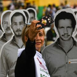 Una mujer se toma una selfie con un cartel con la imagen de su padre, desaparecido por el conflicto bélico, durante una intervención de protesta en la plaza de Bolívar, en Bogotá. | Foto:Juan Barreto / AFP