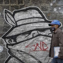 Un hombre camina frente a un grafiti, en Quito, capital de Ecuador. | Foto:Xinhua/Str
