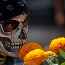 Un hombre disfrazado sostiene flores de cempasúchil, un elemento tradicional de las ofrendas de Día de Muertos, en Xochimilco, en la Ciudad de México. | Foto:Xinhua/Francisco Cañedo