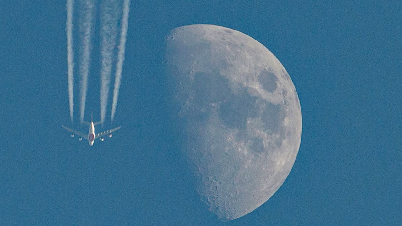 Un avión de línea vuela mientras la luna creciente se eleva sobre Basora, en el sur de Irak. | Foto:Hussein FALEH / AFP