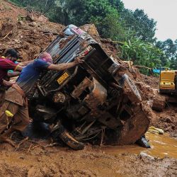 Los trabajadores de rescate empujan un vehículo volcado atascado en el barro y los escombros en un lugar de un deslizamiento de tierra que se afirma que fue causado por las fuertes lluvias en Kokkayar en el estado de Kerala de la India. | Foto:AFP