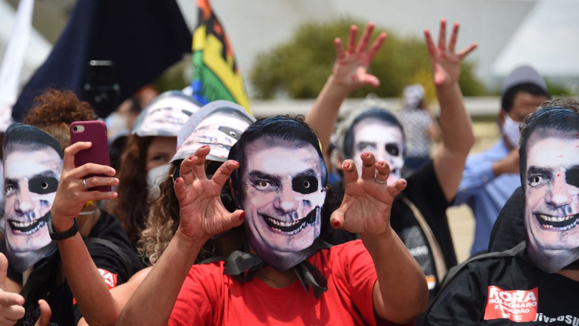 Protesters wearing masks depicting President Jair Bolsonaro protest against government policies in front of Planalto Palace in Brasilia, on October 20, 2021.