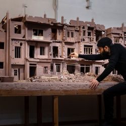 El escultor sirio Khaled Dawwa trabaja en una escultura de arcilla que representa una calle de Siria destruida por la guerra, en Vanves. | Foto:JOEL SAGET / AFP