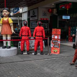 Unas mujeres pasan junto a unas estatuas con personajes de la serie de Netflix Juego de Calamares en un patio de comidas para atraer visitantes en Surabaya. | Foto:JUNI KRISWANTO / AFP