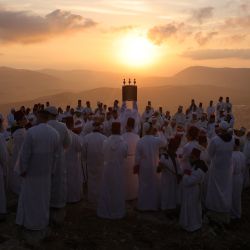 Unos fieles samaritanos sostienen un rollo de la Torá durante una peregrinación tradicional que marca la festividad de Sucot, o Fiesta de los Tabernáculos, en la cima del monte Gerizim, cerca de la ciudad norteña de Nablus, en la Cisjordania ocupada por Israel. | Foto:EMMANUEL DUNAND / AFP