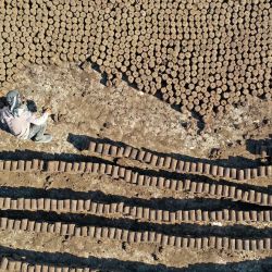 En esta vista aérea, un trabajador alinea tubos de madera de orujo, conocida localmente como "birin", un producto inflamable y ecológico hecho de residuos de aceite de oliva que puede utilizarse para calentar las casas durante el invierno, en una fábrica en la ciudad de Armanaz, en la parte noroeste de la provincia siria de Idlib. | Foto:OMAR HAJ KADOUR / AFP