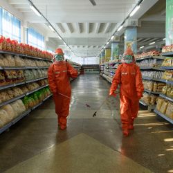 Empleados rocían desinfectante como parte de las medidas preventivas contra el coronavirus Covid-19 en los almacenes Yokjon en Pyongyang. | Foto:KIM WON JIN / AFP