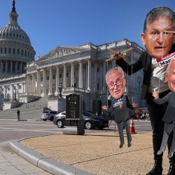 Un manifestante lleva una fotografía del senador Joe Manchin como máscara mientras juega a ser un titiritero en la periferia de una manifestación que destaca los esfuerzos de los demócratas del Congreso para legislar contra el cambio climático fuera del Capitolio de EE.UU. en Washington, DC. | Foto:Chip Somodevilla/Getty Images/AFP