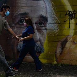 Personas caminan frente a un mural de Albert Einstein en una calle, en el departamento de San Salvador, El Salvador. | Foto:Xinhua/Alexander Peña