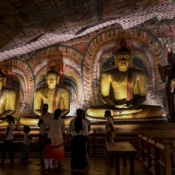 Los visitantes observan las estatuas de Buda dentro de una cueva natural en el Templo de la Roca, también conocido como Rangiri Dambulla Rajamaha Viharaya, en Dambulla, a unos 150 kms al norte de Colombo. | Foto:ISHARA S. KODIKARA / AFP