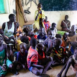 Un grupo de personas se reúne en un aula del campamento de refugiados sursudaneses de Dibba Busin, en el estado sudanés de Nilo Blanco, tras las fuertes inundaciones que destruyeron los refugios. | Foto:ASHRAF SHAZLY / AFP
