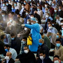 Un trabajador municipal rocía desinfectante mientras los iraníes vestidos con máscaras se reúnen en una mezquita de la capital, Teherán, por primera vez después de que las autoridades suavizaran algunas de las restricciones impuestas durante más de un año en un intento de frenar la propagación del coronavirus. | Foto:AFP