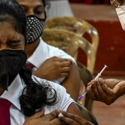 Un trabajador sanitario inocula a una alumna la dosis de la vacuna de Pfizer-BioNTech contra el coronavirus Covid-19 en un centro educativo de Colombo de acuerdo con la directiva del gobierno. | Foto:ISHARA S. KODIKARA / AFP