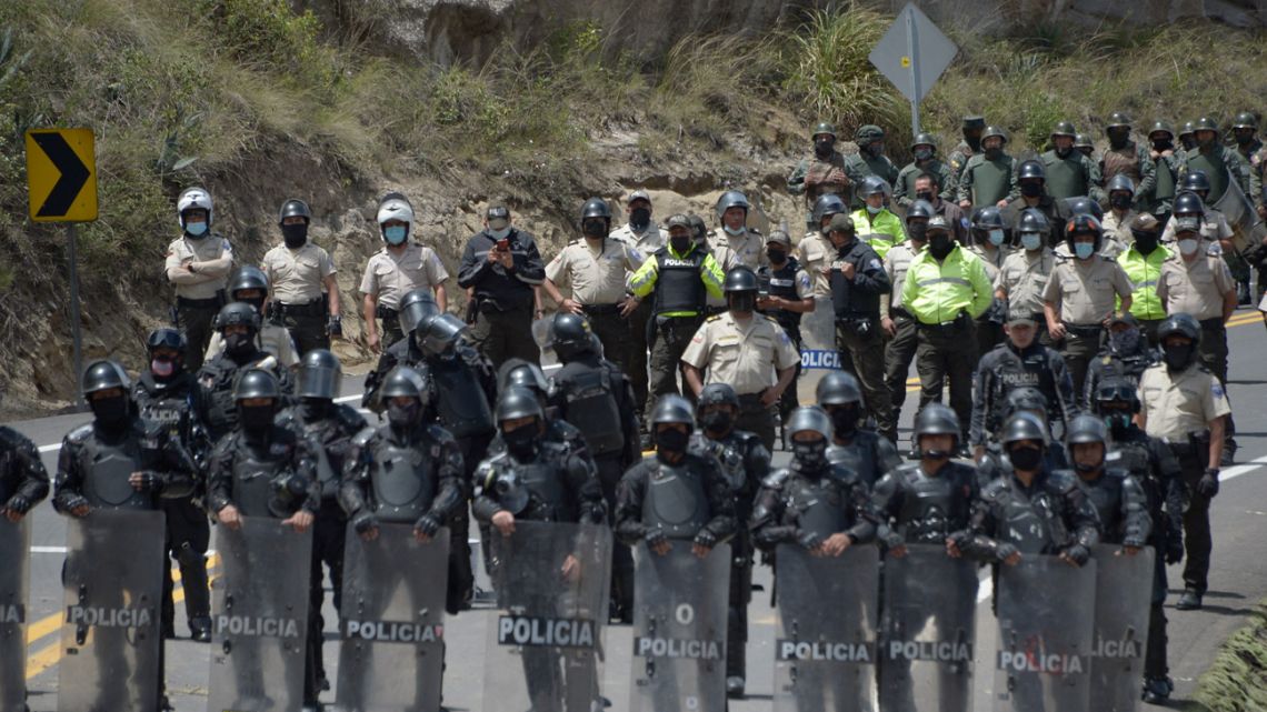 Riot police take position to clear a barricade set up by indigenous people and farmers to block a road in Oton, Pichincha province, Ecuador, on October 27, 2021.