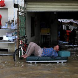 Los residentes miran rodeados por las aguas de las inundaciones en las afueras de Phnom Penh, tras las fuertes lluvias monzónicas. | Foto:TANG CHHIN SOTHY / AFP