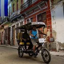 Un bicitaxi circula por una calle en La Habana. | Foto:YAMIL LAGE / AFP