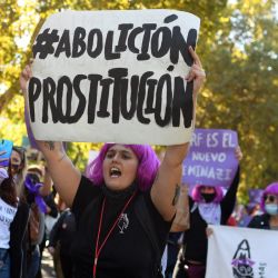 Una mujer sostiene un cartel que exige la abolición de la prostitución durante una manifestación con el lema "La fuerza de las mujeres es el futuro de todos" en Madrid. | Foto:OSCAR DEL POZO / AFP