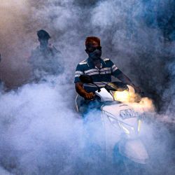 La gente camina entre el humo mientras los trabajadores de la Corporación Municipal del Sur de Delhi fumigan una zona para evitar que los mosquitos se reproduzcan en Nueva Delhi. | Foto:PRAKASH SINGH / AFP