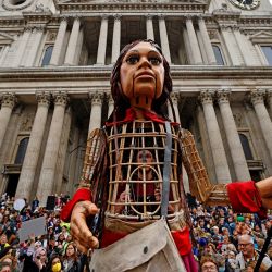 La pequeña Amal, una marioneta gigante que representa a una niña refugiada siria, está rodeada de simpatizantes frente a la catedral de San Pablo, en la ciudad de Londres, como parte del proyecto artístico internacional The Walk. | Foto:Tolga Akmen / AFP