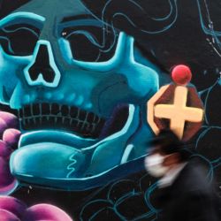 Una persona camina frente al mural de la artista boliviana "Ñusta" en uno de los muros del Cementerio General de La Paz durante el evento anual de muralismo "Ñatinta 2021", en La Paz, Bolivia. | Foto:Xinhua/Mateo Romay