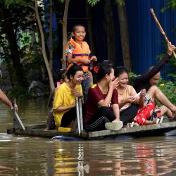 Personas sentadas en una balsa mientras se abren paso a través de las aguas de la inundación en las afueras de Phnom Penh, tras las fuertes lluvias monzónicas. | Foto:TANG CHHIN SOTHY / AFP