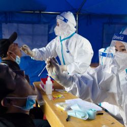 Personal médico toma una muestra de hisopo de un hombre para ser analizado por el coronavirus Covid-19 en el distrito de Ganzhou en Zhangye, en la provincia noroccidental china de Gansu. | Foto:AFP
