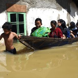 Una familia evacua su casa inundada tras las fuertes lluvias en Bandung. | Foto:Timur Matahari / AFP