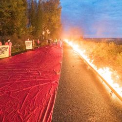 Activistas de Greenpeace se sitúan junto a una línea roja simbólica bordeada de fuego en el borde de la mina de lignito a cielo abierto de Garzweiler, cerca de Luetzerath, en el oeste de Alemania, mientras protestan contra la ampliación de la mina. | Foto:Bernd Lauter / AFP
