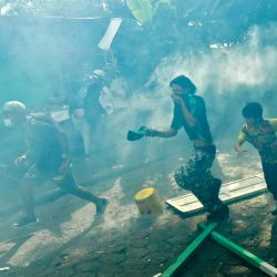 Personas huyen de los gases lacrimógenos disparados por la policía antidisturbios en el barrio de Moravia mientras las autoridades locales intentan aplicar una orden de desalojo para evacuar a las familias que viven en supuestas construcciones ilegales, en Medellín, Colombia. | Foto:JOAQUIN SARMIENTO / AFP