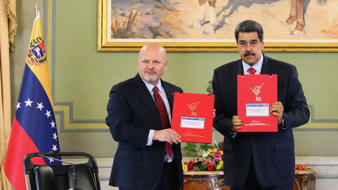 Handout photo released by the Miraflores presidential palace press office showing Venezuela's President Nicolás Maduro (right) while showing documents with the Prosecutor of the International Criminal Court (ICC), Karim Khan, (left) at the Miraflores presidential palace in Caracas on November 3, 2021. Khan arrived Sunday in Venezuela as part of a 10-day tour in Latin America. 