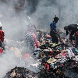 Comerciantes recogen ropa de los escombros quemados por el fuego a primera hora de la mañana en el mercado de Gikomba, el mayor mercado de ropa de segunda mano de África Oriental, en Nairobi, Kenia. | Foto:Yasuyoshi Chiba / AFP
