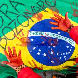 Un manifestante muestra sus manos pintadas de rojo delante de una bandera brasileña durante una manifestación contra el MERCOSUR, en Bruselas, originada por 'Rise For Climate Belgium' y la 'Asociación Jiboiana', que trabaja con los pueblos indígenas para proteger la selva amazónica. | Foto:HATIM KAGHAT / Belga / AFP