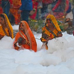 Los devotos realizan rituales religiosos mientras ofrecen oraciones al dios Sol mientras están de pie en las aguas del río Yamuna cubiertas de espuma contaminada con motivo del festival hindú de Chhat Puja en Noida, India. | Foto:MONEY SHARMA / AFP