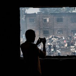 Un hombre utiliza un celular para tomar una foto de los restos humeantes que fueron quemados por el fuego a primera hora de la mañana en el mercado de Gikomba, el mayor mercado de ropa de segunda mano de África Oriental, en Nairobi, Kenia. | Foto:Yasuyoshi Chiba / AFP