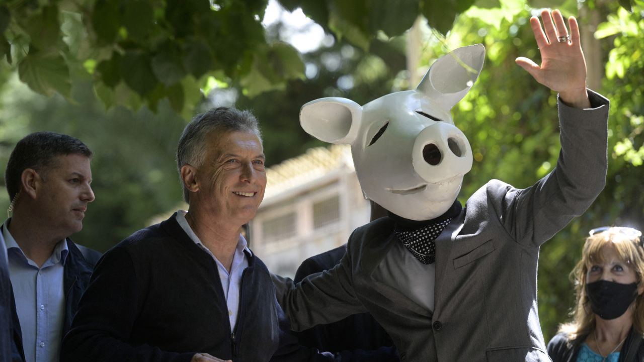 El ex presidente Mauricio Macri posa para una foto junto a un hombre con una máscara de cerdo, antes de emitir su voto durante las elecciones legislativas. | Foto:JUAN MABROMATA / AFP