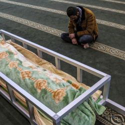 Un hombre se sienta en una mezquita junto al cuerpo repatriado del migrante kurdo iraquí Gailan Diler, que murió al intentar cruzar ilegalmente a Polonia a través de Bielorrusia, durante su funeral en Arbil, la capital de la región autónoma kurda del norte de Irak. | Foto:SAFIN HAMED / AFP