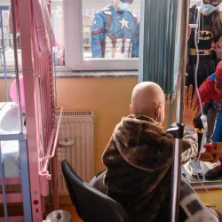Personas disfrazadas de superhéroes de dibujos animados entretienen a un niño diagnosticado de cáncer en el hospital infantil de Pristina, un evento organizado por Care for Kosovo Kids que proporciona todos los medicamentos para el tratamiento de los pacientes diagnosticados de cáncer. | Foto:ARMEND NIMANI / AFP