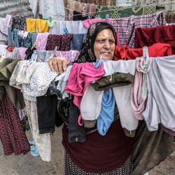 Una mujer mira mientras está detrás de la ropa colgada para secar en un tendedero en el campo de Rafah para los refugiados palestinos en el sur de la Franja de Gaza. | Foto:SAID KHATIB / AFP